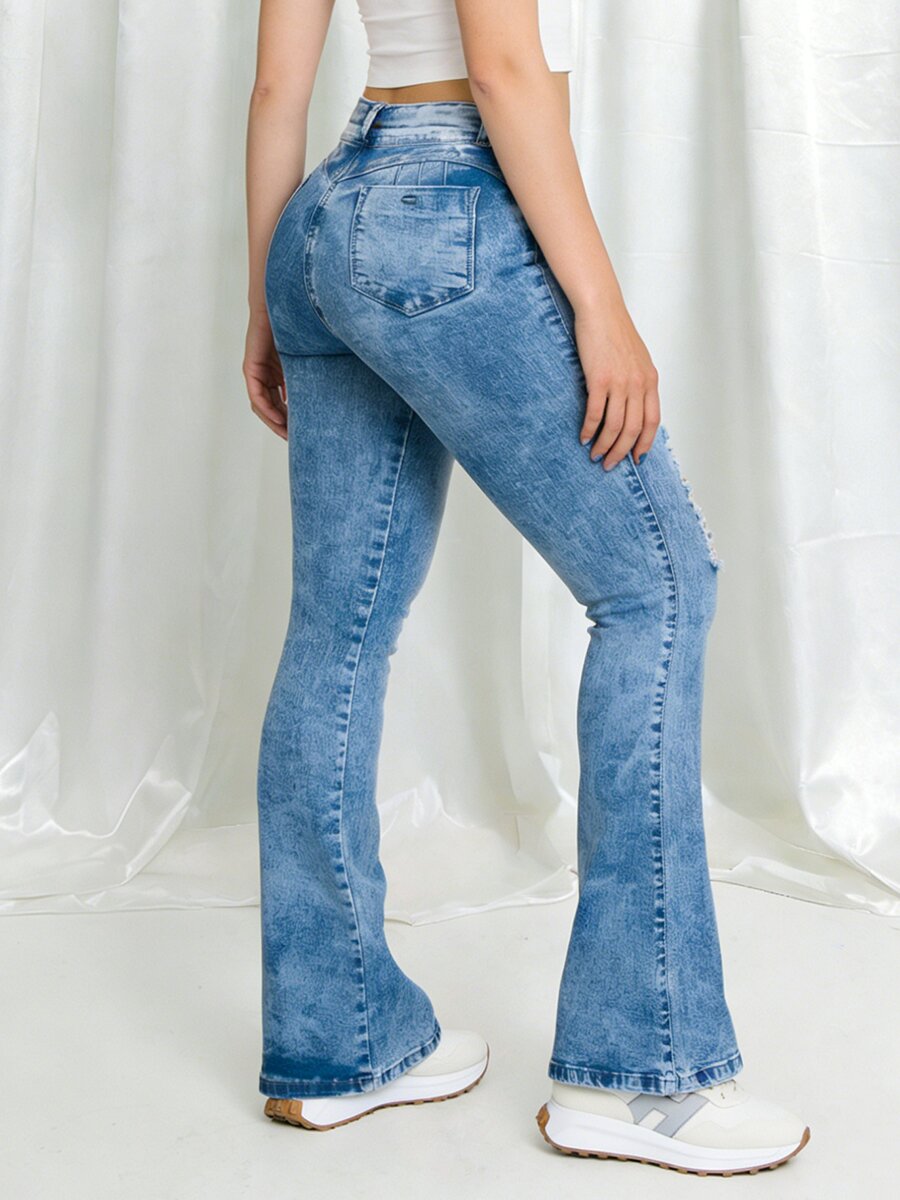 Close up of ripped details and stretch denim fabric on classic blue bootcut jeans for women – sexy butt lifting pants decoration shot