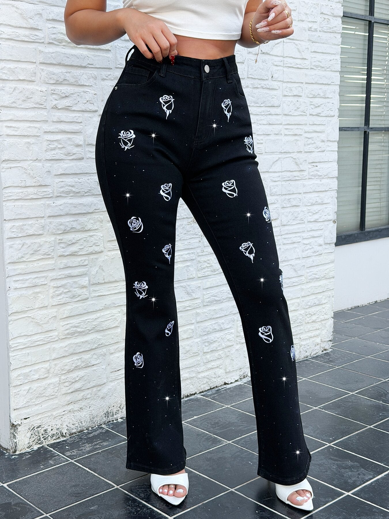 Close up of white rose embroidery and rhinestone details on vintage bootcut jeans for women – stretch flare denim pants decoration shot