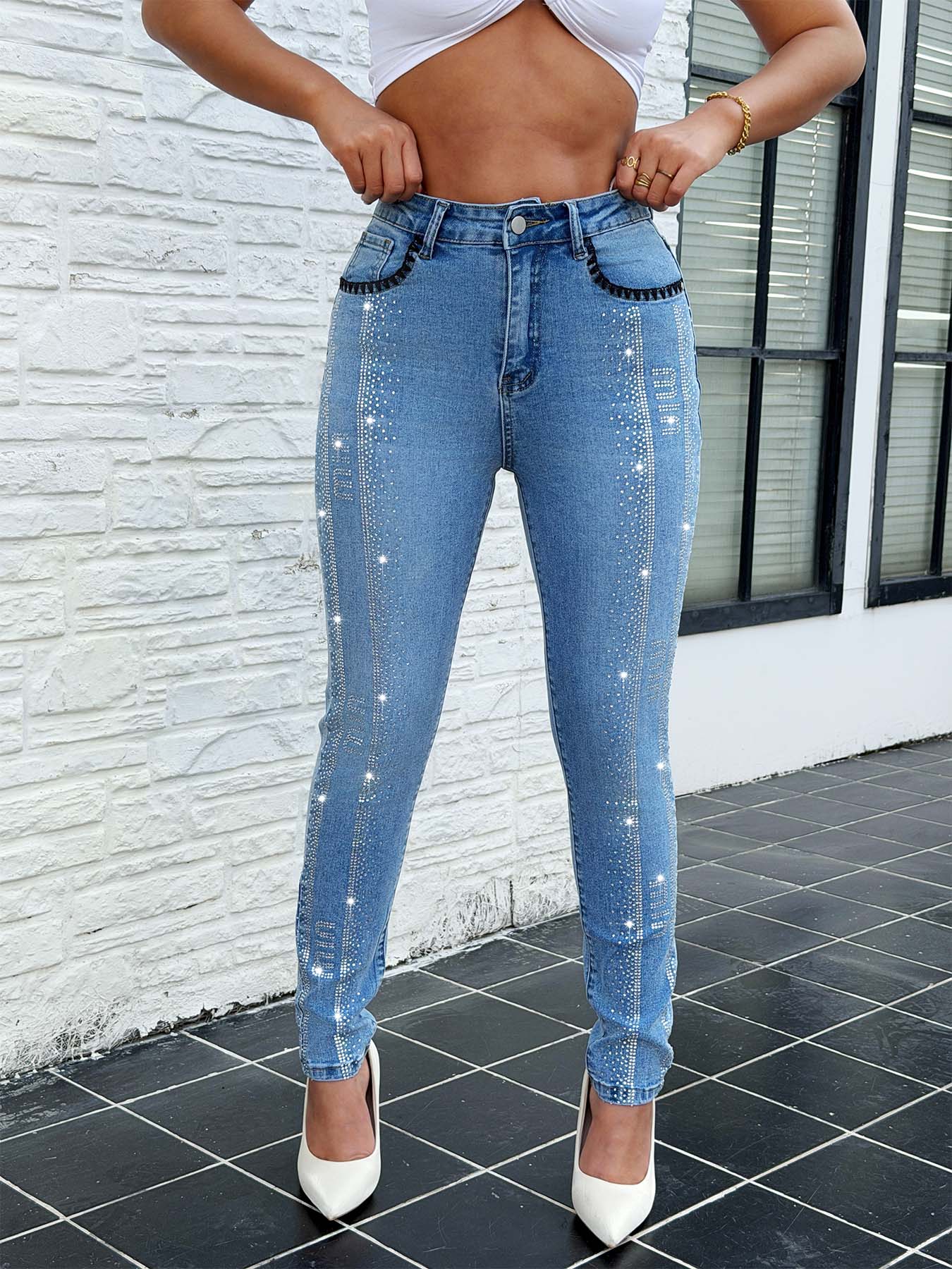 Flat lay of vintage rhinestone embroidery pocket jeans for women – black thread stretch skinny denim pants in blue with sparkly embellishments on white background
