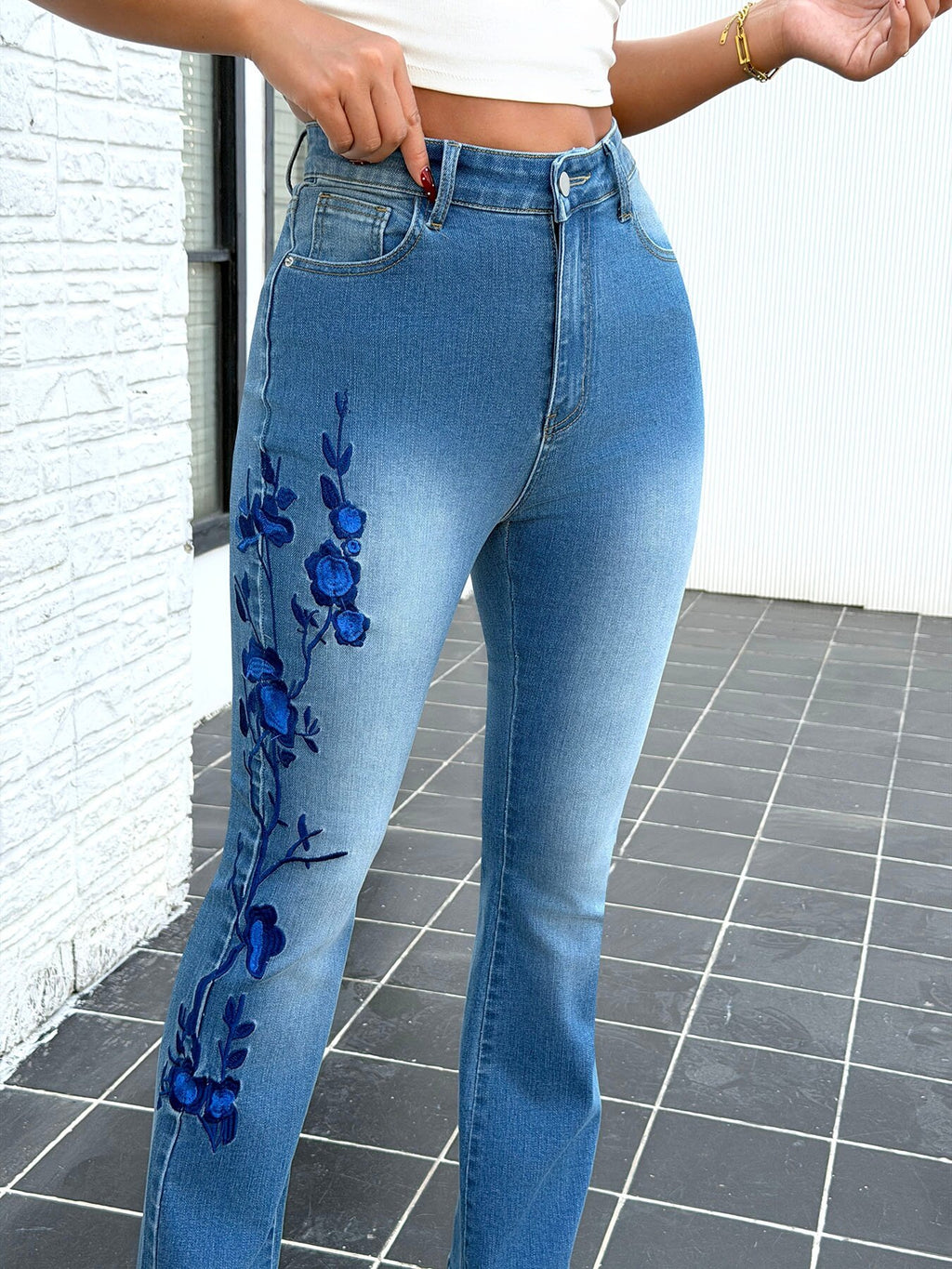 Close up of blue embroidery details on vintage flare jeans for women – elegant stretch slim fit denim pants decoration shot